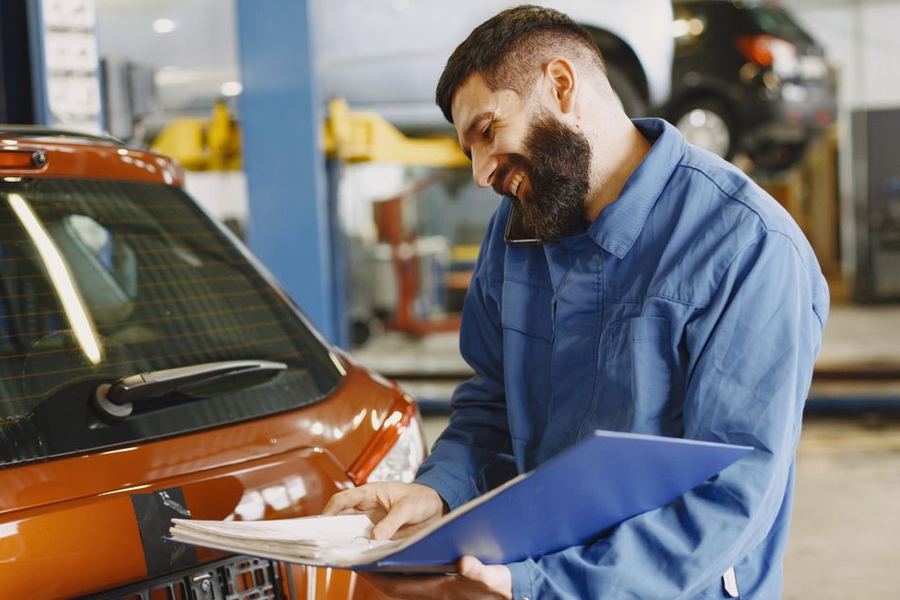 Mechanic reviewing a repair order next to a car