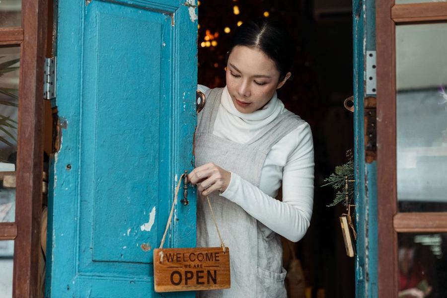Shop owner flipping the open sign at her store