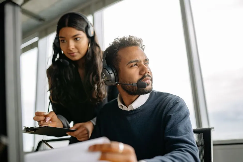 Two support specialists with headsets working at a screen